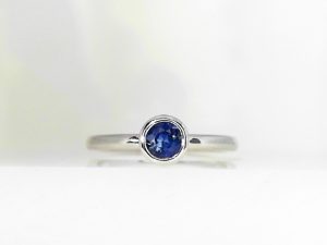Lady's White 14 Karat Bezel Set Fashion Ring Size 7 With One 0.33Ct Round Blue Sapphire Diamond Cut