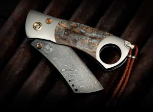 The Epic
FEATURES & SPECS
Dimensions:
Blade: 2.75"
Handle: 3.75"
Open: 6.
 is truly epic, without equal in the world of exotic cigar cutters. The thru hole in the titanium frame will accommodate up to a 52 gauge cigar, and the single sided precisionground damascus blade cuts cleanly thru your preferred smoke. The damascus is our stainless 'Boomerang' pattern by Chad Nichols featuring three alloys forged together into a tapestry in steel with an optimum hardness of HRC 59 for wear resistance. Inlayed fossil wooly mammoth tooth is hand-polished to fine luster, and citrine gemstones, copper, stainless, and sterling hardware complete the presentation. This piece works beautifully as a cigar cutter and general purpose pocket knife!  #265 of 500

FEATURES & SPECS
Dimensions:
Blade: 2.75"
Handle: 3.75"
Open: 6.

FOSSIL MAMMOTH TOOTH
From a Woolly Mammoth that walked the Earth at least 10,000 years ago.
Modern humans coexisted with woolly mammoths during the Upper Paleolithic period when they entered Europe from Africa between 30,000 and 40,000 years ago. Prior to this, Neanderthals had coexisted with mammoths during the Middle Paleolithic and up to that time. Woolly mammoths were very important to Ice Age humans, and their survival may have depended on these animals in some areas.

The woolly mammoth is the next most depicted animal in Ice Age art after horses and bisons, and these images were produced up to 11,500 years ago. Today, more than five hundred depictions of woolly mammoths are known, in media ranging from carvings and cave paintings located in 46 caves in Russia, France and Spain, to sculptures and engravings made from different materials.

William Henry's fossil Mammoth tooth is harvested in Alaska and Siberia. It is a rare and mesmerizing material, a living testimony of the dawn of Mankind.