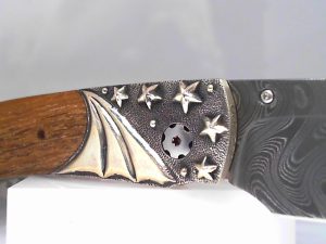 The Spearpoint ‘Iwo Jima’ features a beautiful frame in hand-carved sterling silver by Lee Downey, inlaid with teak wood from the USS California battleship, reclaimed when it was decommissioned in 1959. The blade is hand forged 'Boomerang' damascus by Chad Nichols; the one-hand button lock and the thumb stud are set with blue topaz gemstones. A remarkable instrument with a full-size secure grip and versatile deep-belly blade, the Spearpoint epitomizes William Henry’s core philosophy – that superlative function deserves to be elevated to superlative art. The ‘Iwo Jima’ features some of the most exotic materials, artistry and forged metals that are the hallmark of William Henry's collections; a timeless heirloom to be proudly worn and used for a lifetime before being handed-down to another generation.

Product SKU: B12 IWO JIMA

One-hand button lock system

Dimensions:

Blade 3.06" (77.7mm)
Handle 4.13" (104.9.5mm)
Overall open 7.19" (182.6mm)

All William Henry knives feature a unique serial number which is engraved into the blade to assure the authenticity and lifetime traceability of the product